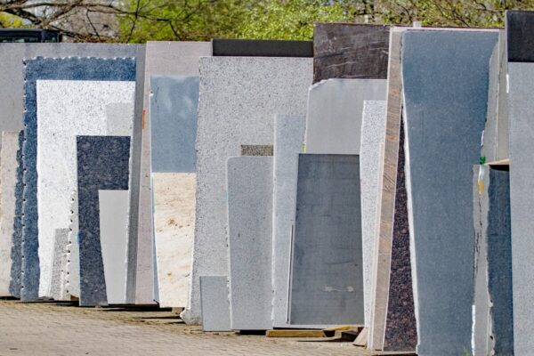 Płyty kamienne ustawione w rzędzie na zewnątrz zakładu kamieniarskiego.