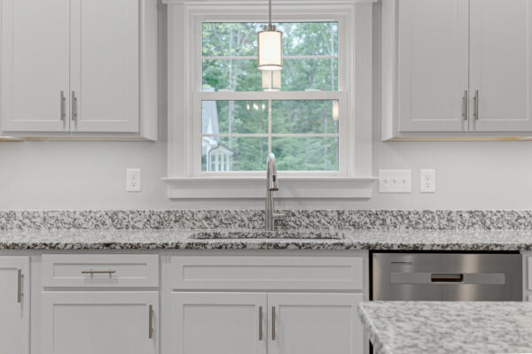 Jasna kuchnia z granitowymi blatami kuchennymi i dużym oknem.