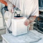 Kamieniarz poleruje marmurowy blok w warsztacie.